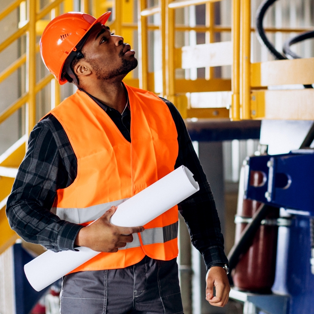 african american worker standing in uniform wearing a safety hat in a factory